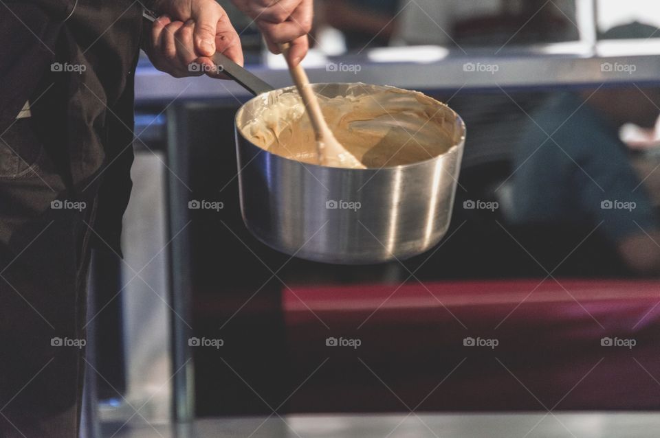 Chef stirring melted caramel in pot 