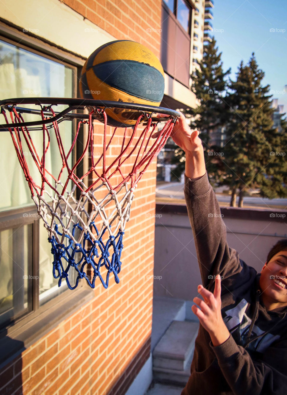 Teen boy is practicing basketball shots