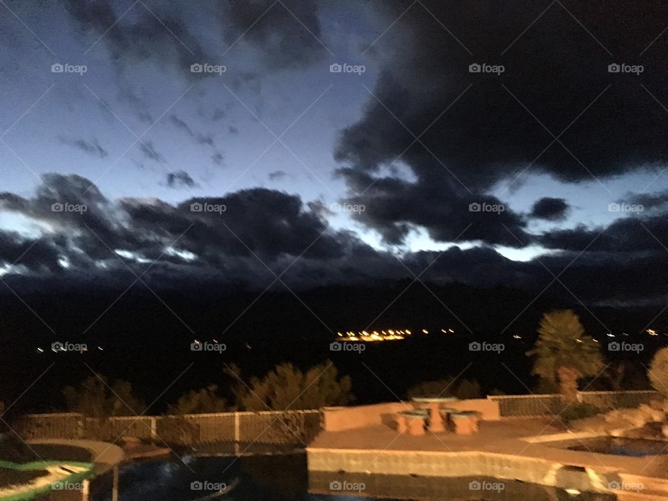 Storm rolling in over backyard pool overlooking valley and distant city lights
