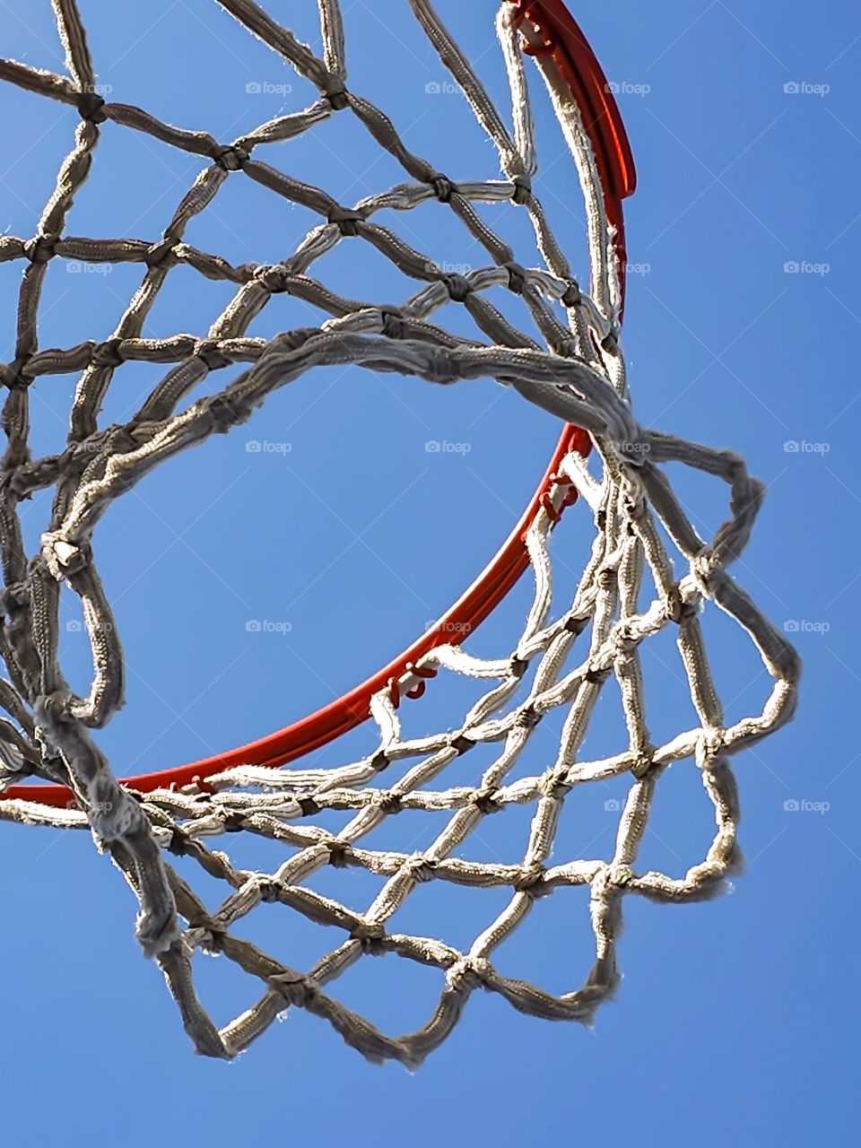 Basketball net on a beautiful sunny afternoon waiting for those slam dunks during game play 