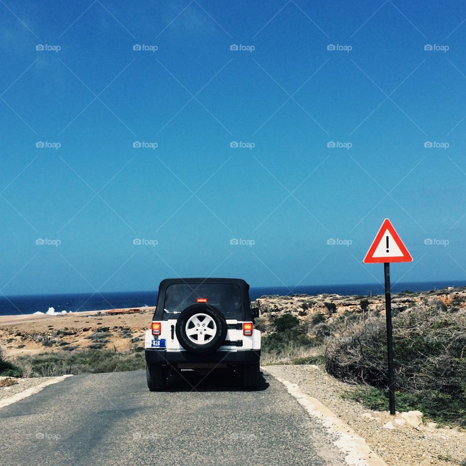Seaside cliffs of Aruba, off-roading in a Jeep, a red caution sign as a warning, we head off into the unknown for a wild adventure