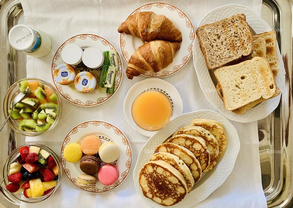 Breakfast from above, croissants, toasted bread and pancakes from above, macarons, fruit salad, healthy yummy breakfast 