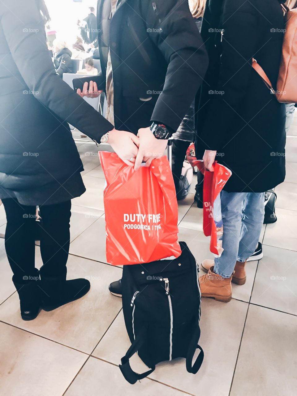 A young couple at the airport with luggage and red bag from Duty Free 