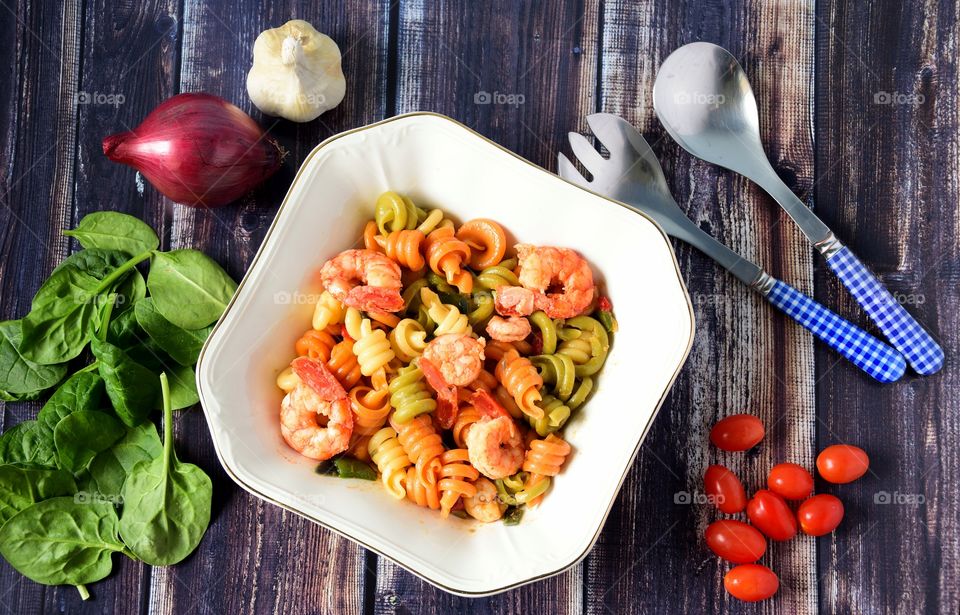 Pasta with prawns and vegetables on wooden table