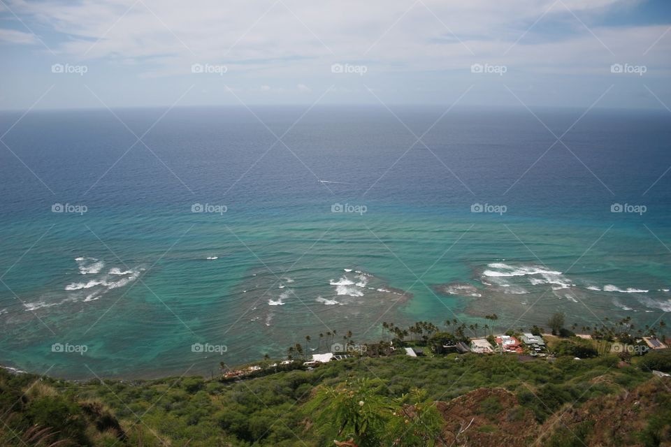 View from Diamond Head. Aquamarine water turns deep blue off the coast of Oahu. Oceanside homes dot the shore.