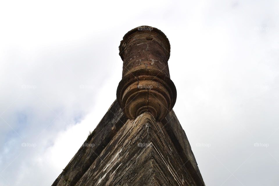 The top of a building that looks like a castle against a grey cloudy sky