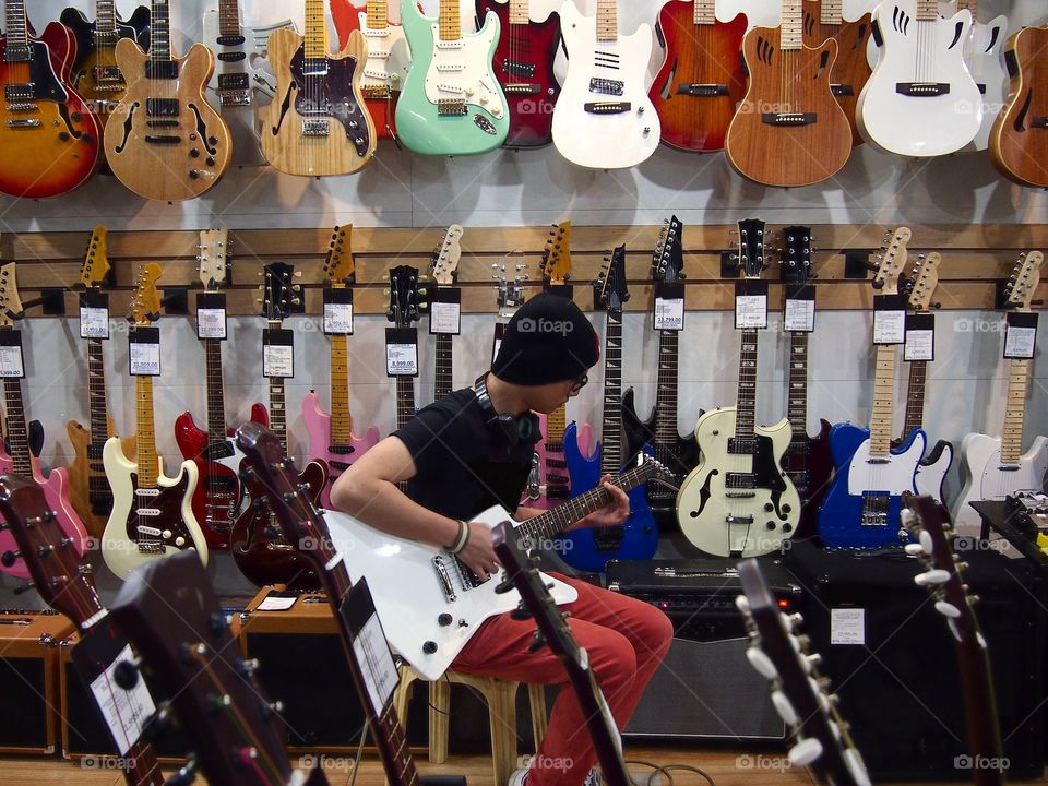 young teen playing guitar in a guitar store