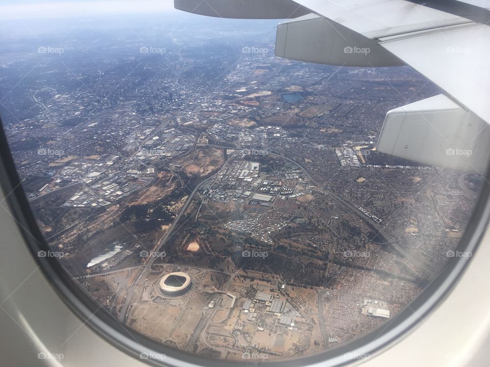 View from the cabin of an Air France Airbus A380 aircraft descending over Johannesburg, South Africa. The Soccer City football stadium can be seen to the bottom left. In winter.