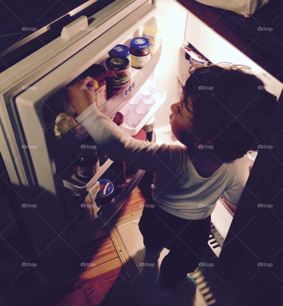 Chlopiec szuka jedzenia w lodowce