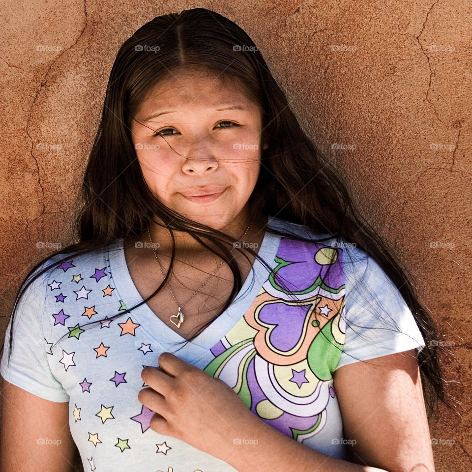 Native American girl posing front of camera in pueblo.