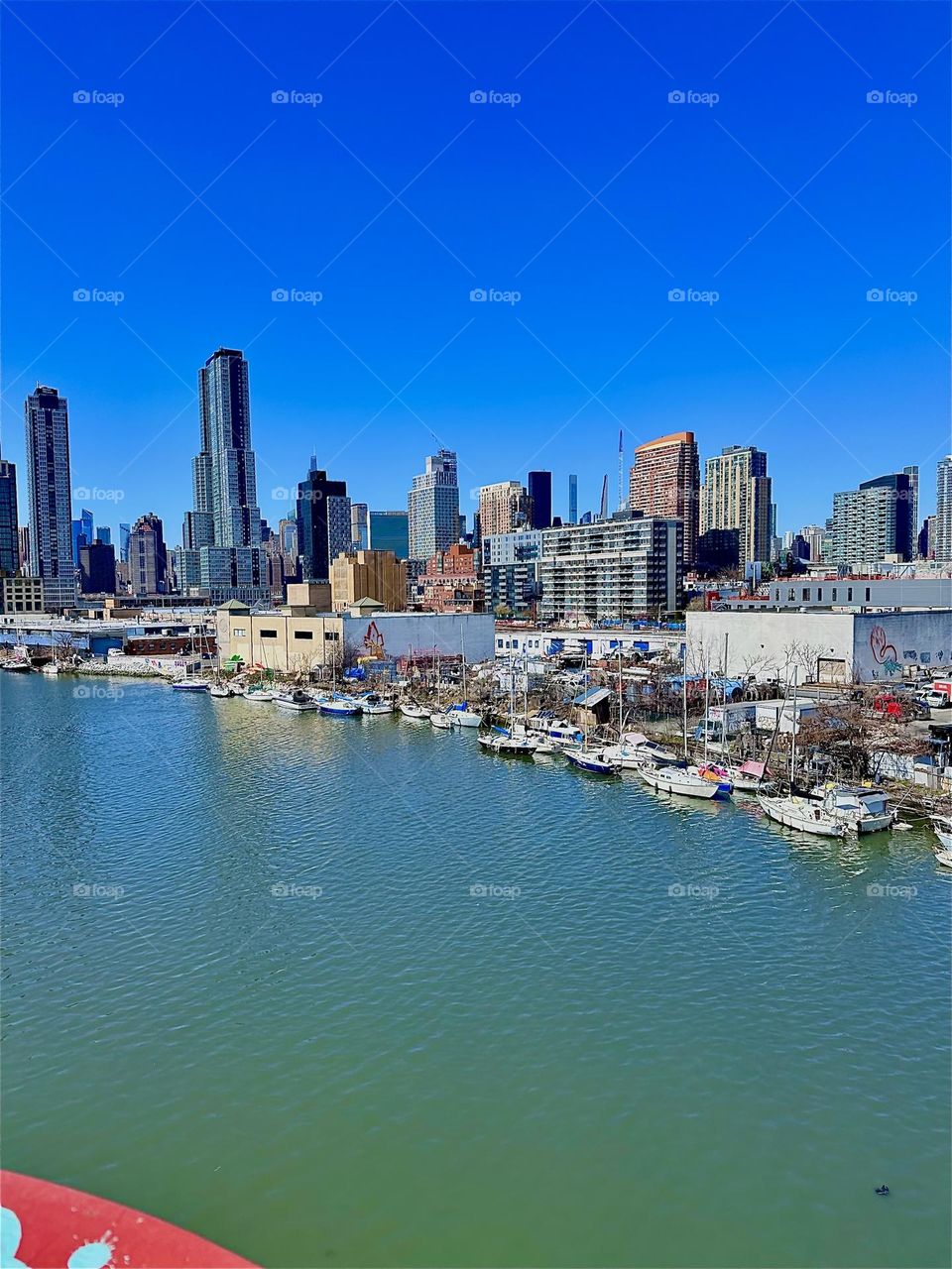 This is beautiful “Newtown Creek” with its great variety of boats seen from the “Pulaski Bridge” that connects LIC, Queens to “Greenpoint”, Brooklyn. Behind the LIC high rises we can see “Manhattan”. 2024. Hypnotic Productions