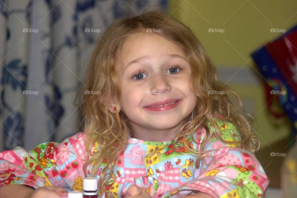 A cute little girl, wearing her strawberry shortcake nightgown, smiling for the camera 