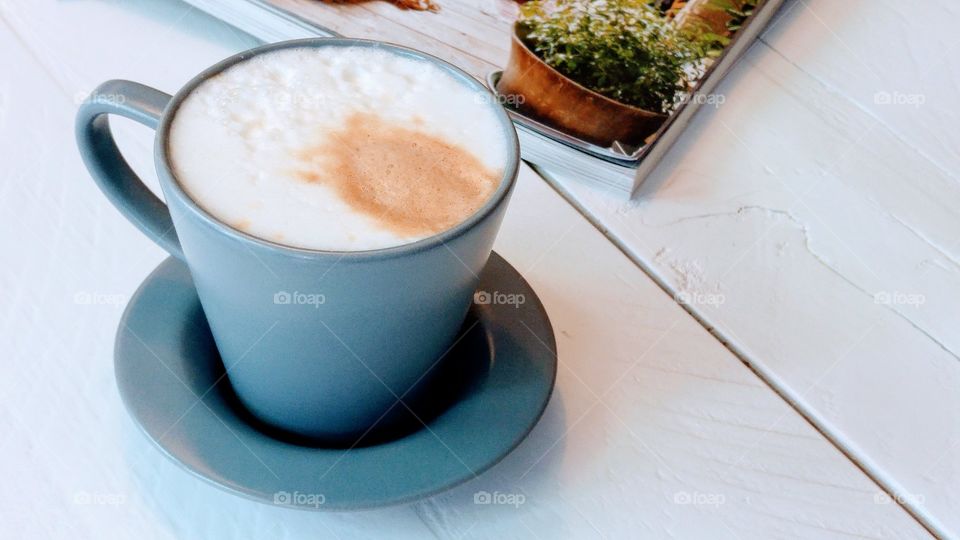cup of coffee on a white wooden table with magazine