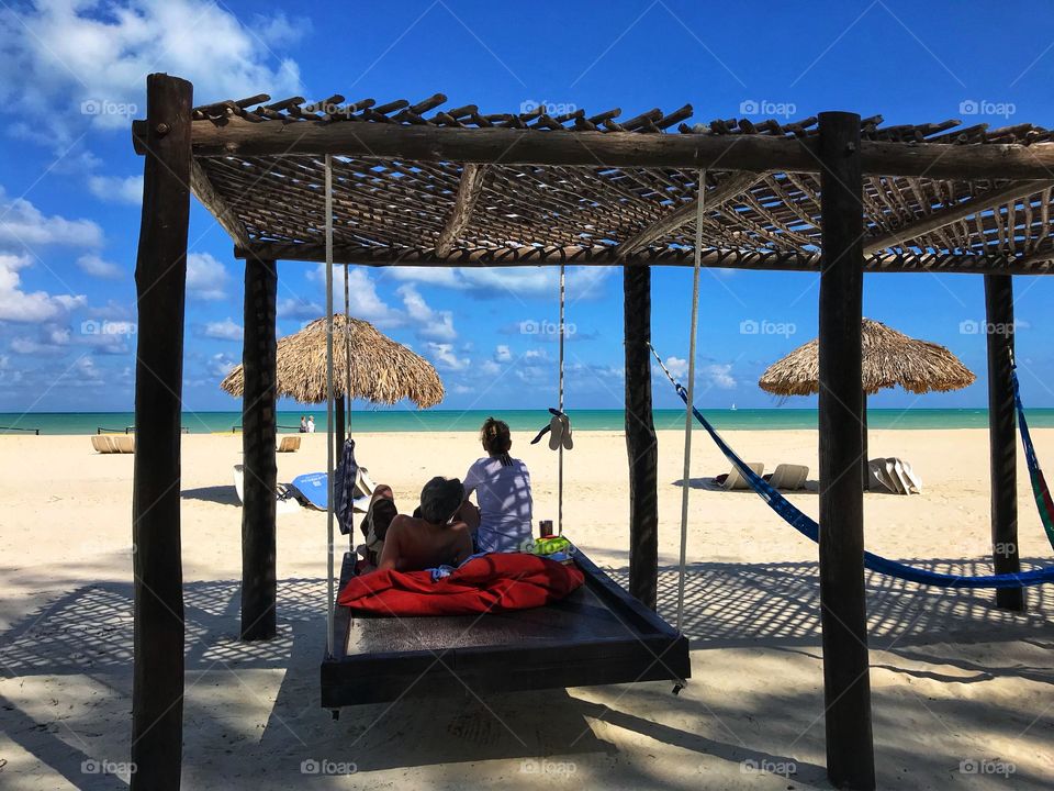 Couple sitting in swinging bed on beach 