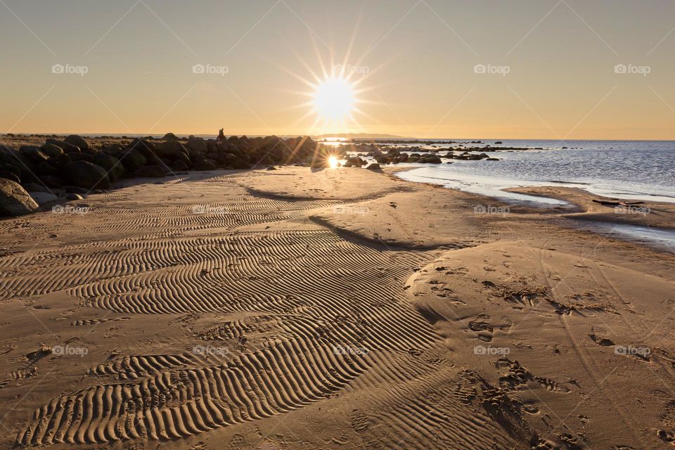 Beautiful sunset by the ocean, wave pattern in the sand 