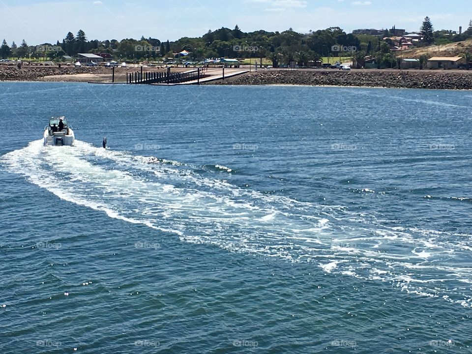 Speedboat in harbour marina leaving its wake 