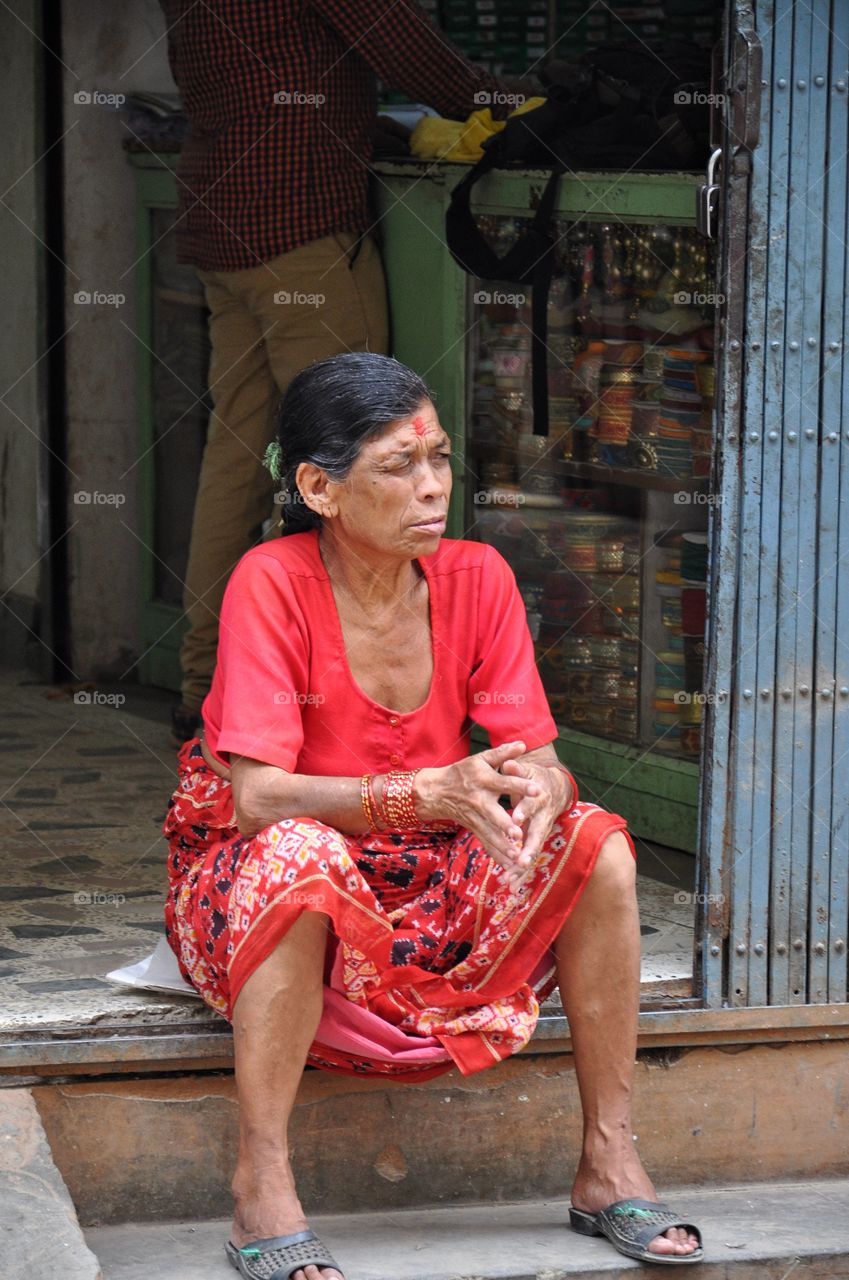 old nepalese woman sitting in the street of kathmandu, nepal