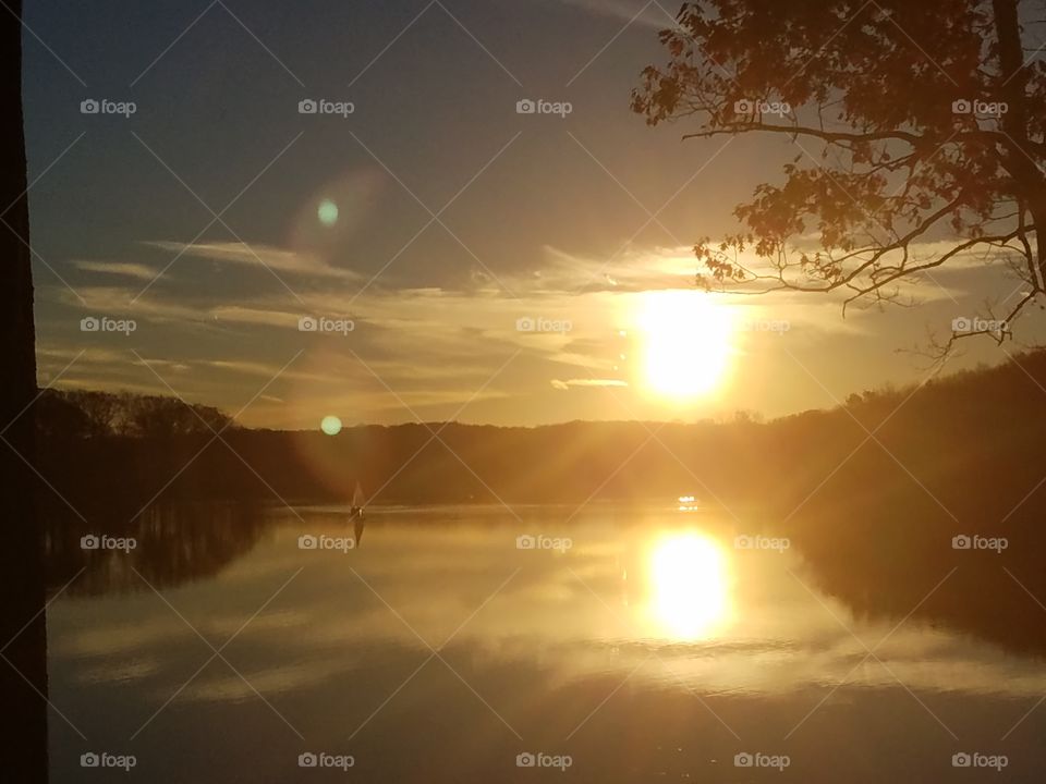 Sunlight reflecting on lake and a sailboat