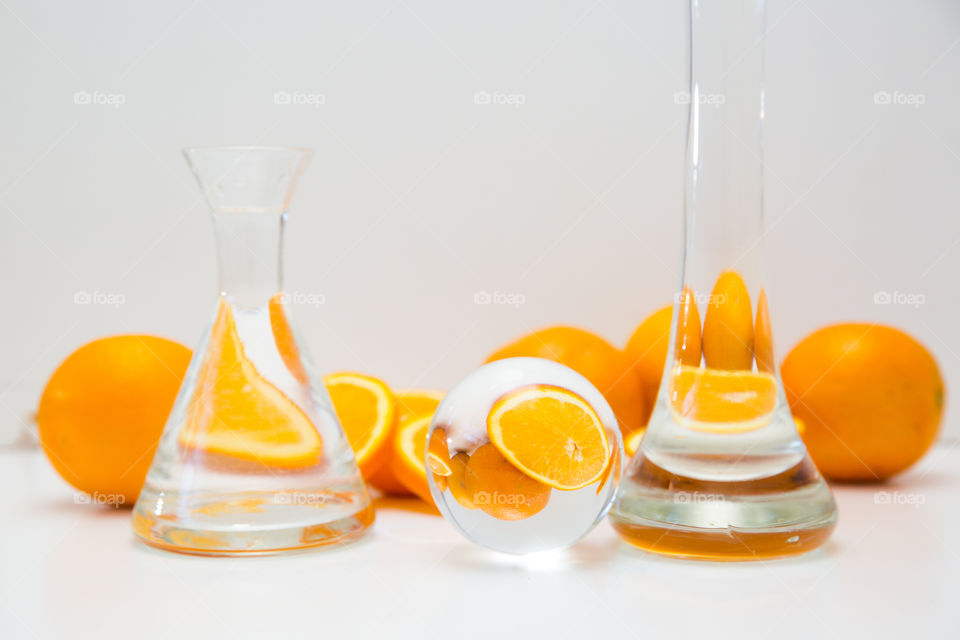 Abstract reflection of oranges through glass objects on white background