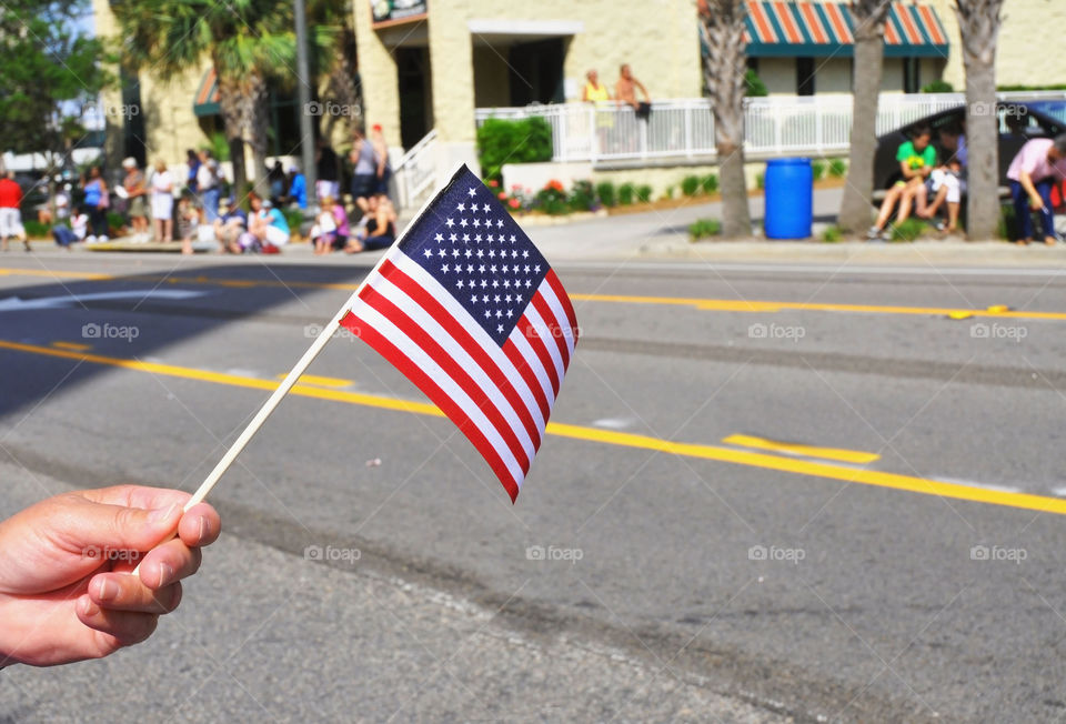 A person holds the American flag along a parade route.