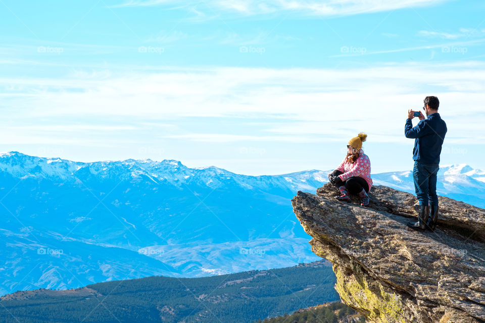 Couple taking pictures at mountain top against glacier in Spain.