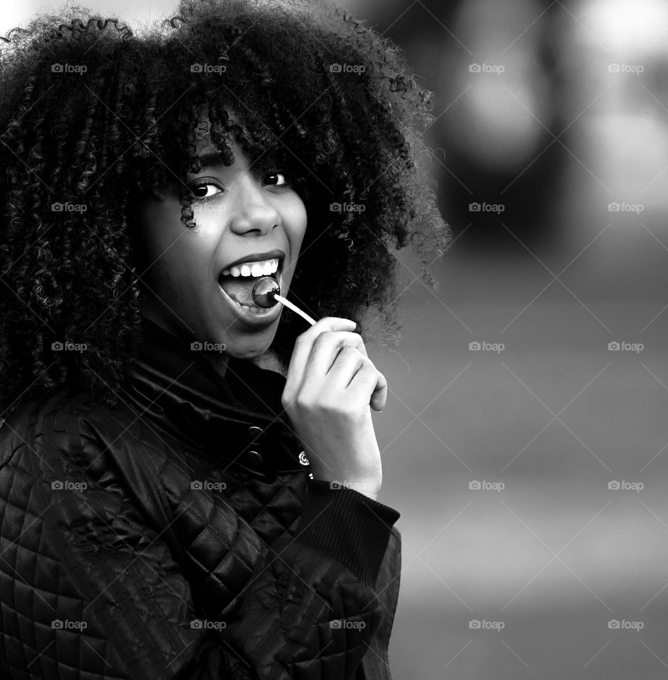 Black and White portrait of African girl eating a lollipop and smiling at camera