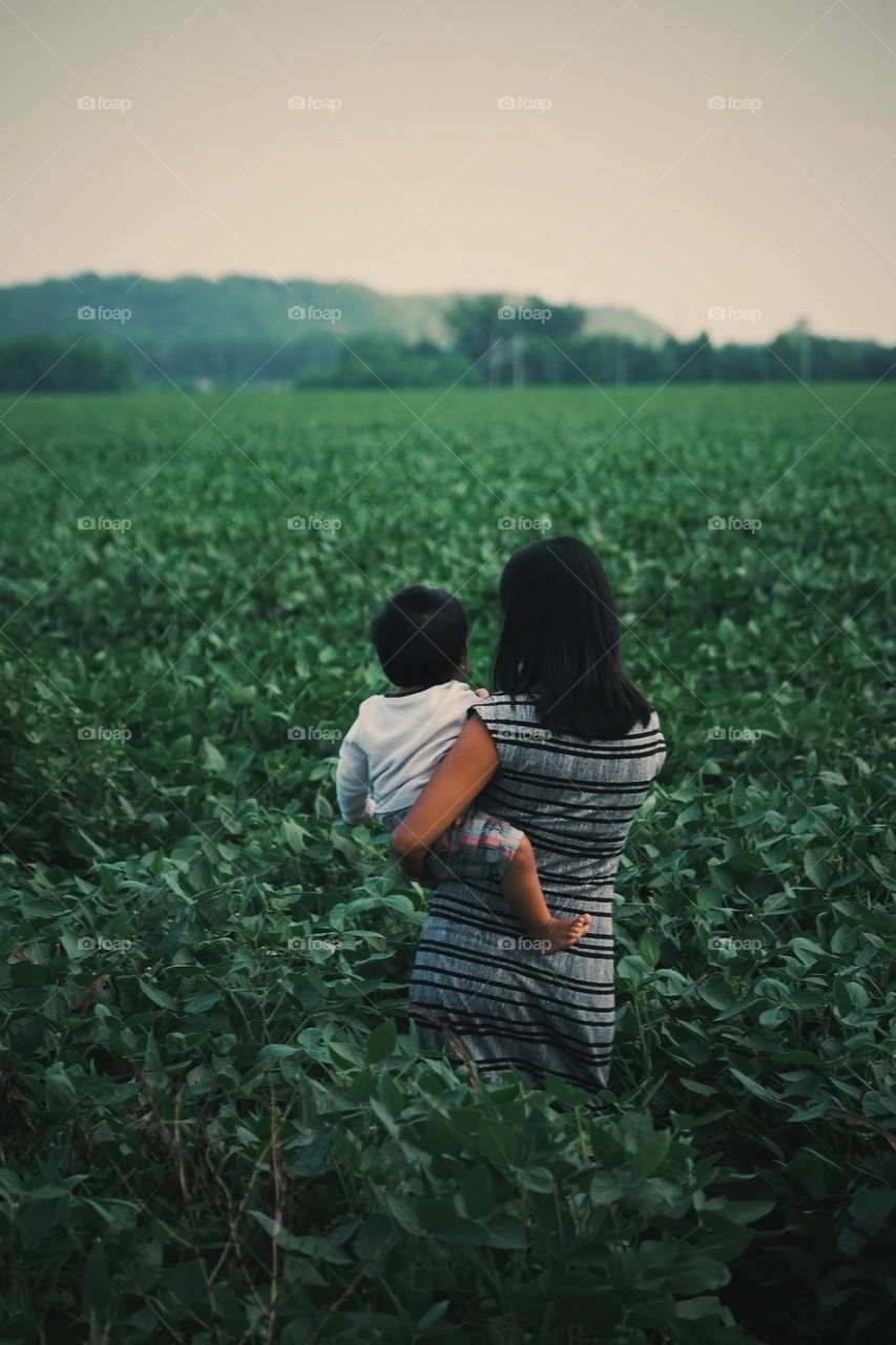 Woman holding baby in field, woman with baby, mother’s tender moments, mother’s love, mother and son, Missouri field, open land in Missouri, green countryside 