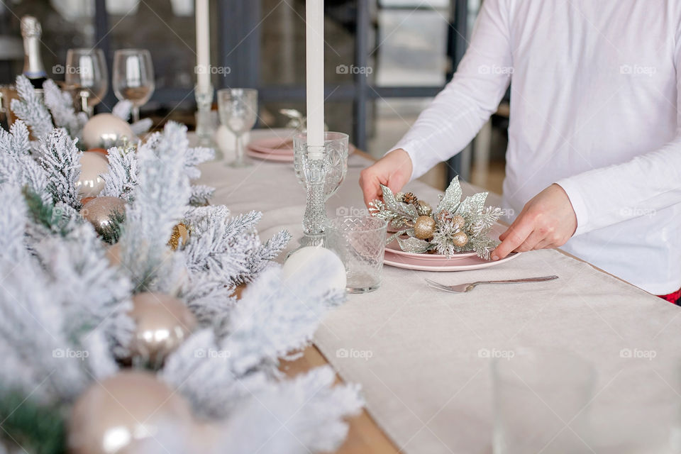 man sets a beautiful decorated winter table for a festive dinner.  Merry Christmas and Happy New Year.