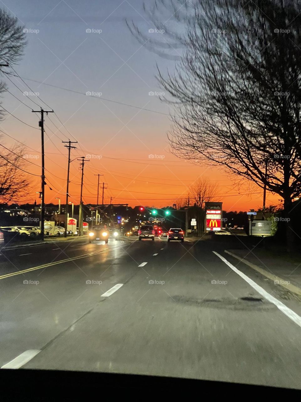 A joy ride, down a busy street, where a road has been traveled, where a moment is waiting and floating to the next. Questions of going and coming. Food is awaiting just beyond the sunset, or before. People with people in the car. 