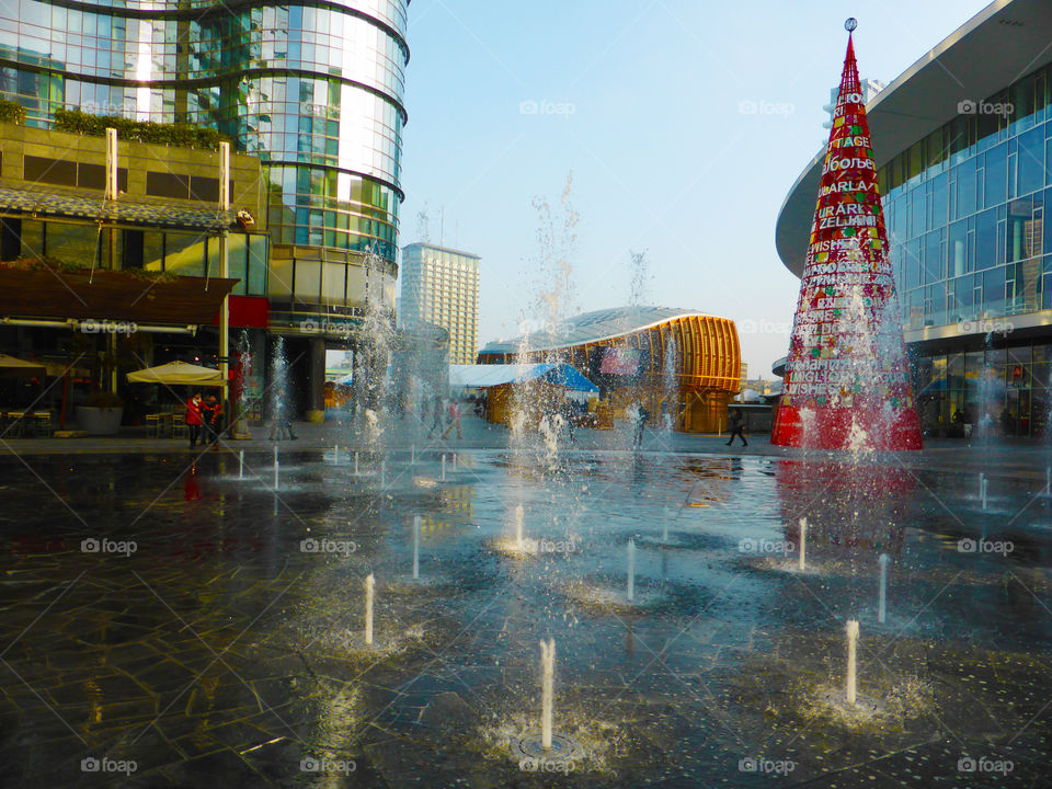 A square of Milan with a beautiful fountain and beside a minimal christmans tree