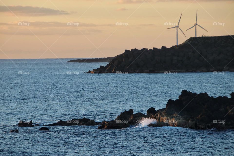 View over the atlantic ocean at sunset with cliffs and wind turbine 