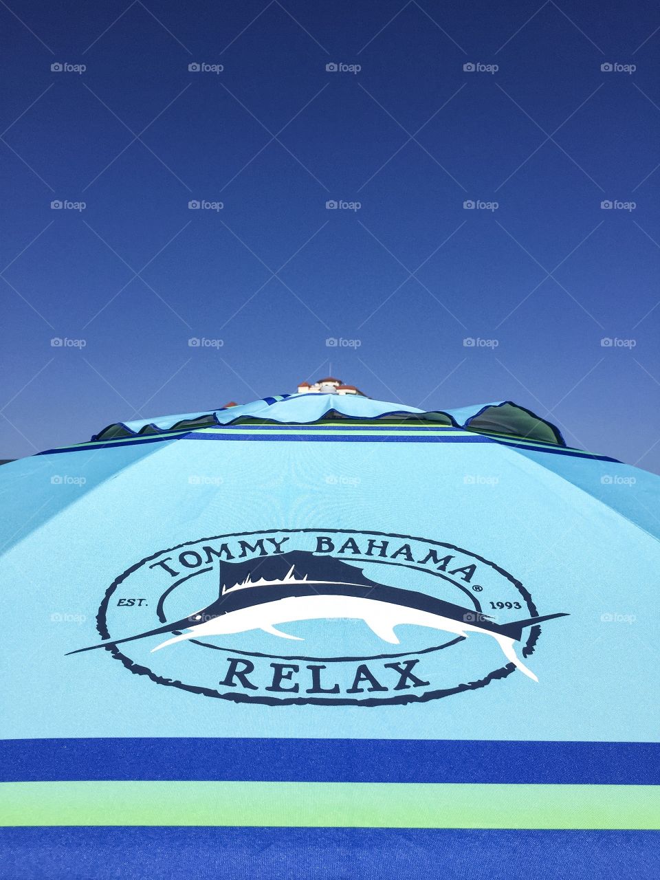 Tommy Bahama beach umbrella against a bright blue sky plenty of room for your text.