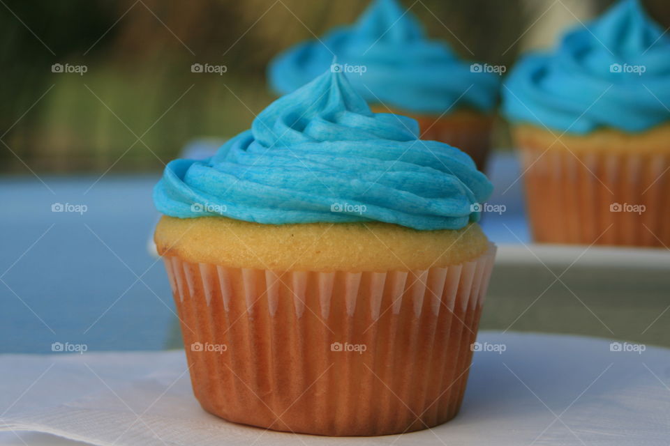 Yellow cupcake with buttercream icing tinted blue. 