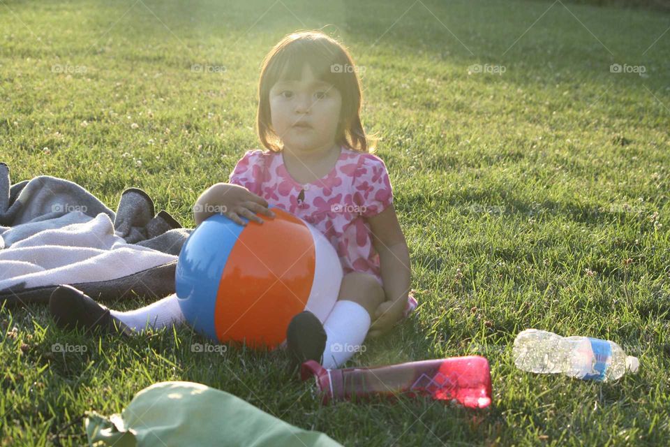 Cute little girl is sitting on the grass