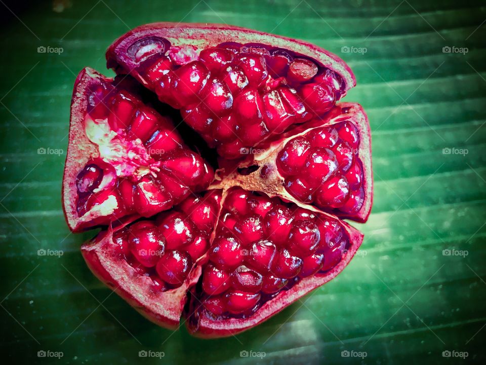 Red ripe pomegranate, (Punica granatum) on banana leaf background