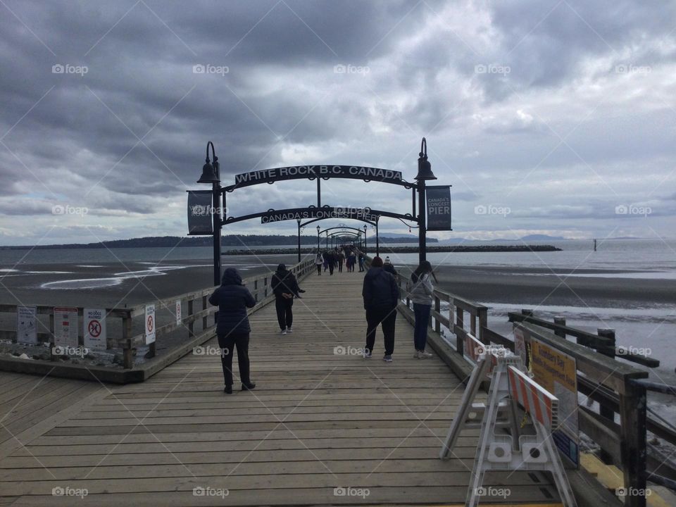 Canada's longest pier in White Rock, British Columbia with people walking along and clouds overhead 