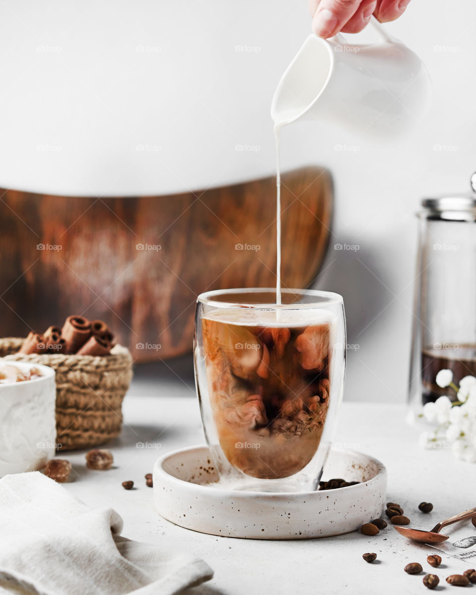 woman hand pouring milk in a glass of coffee