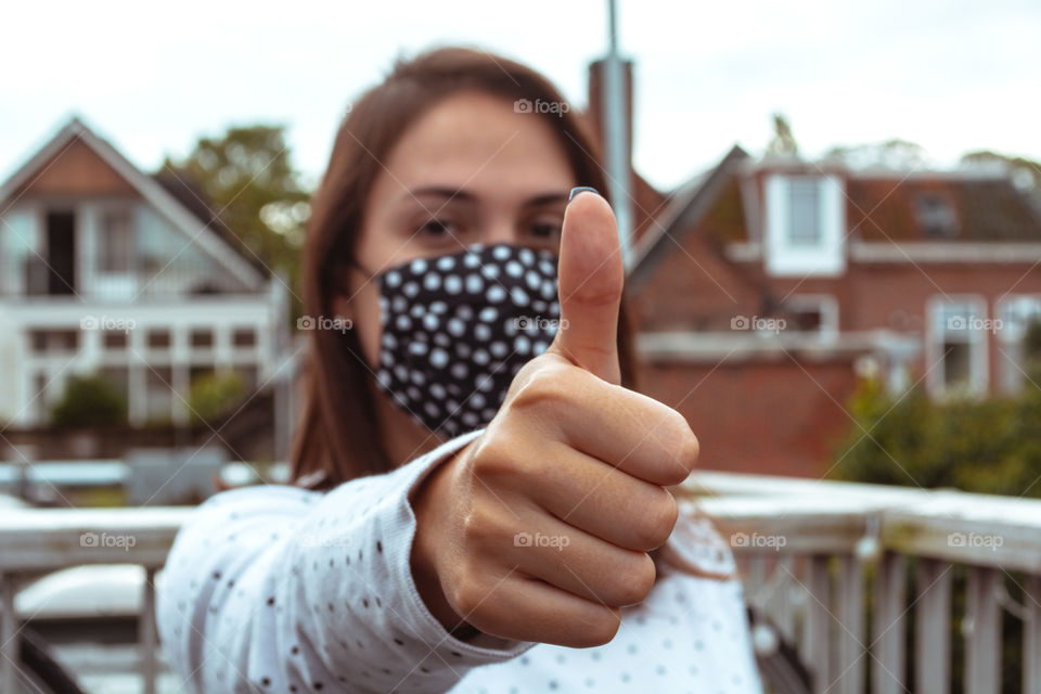 Woman wearing a face mask making a positive sign