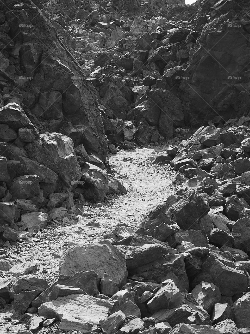 A rocky path winds uphill through towering obsidian fields in Central Oregon on a fall day. 