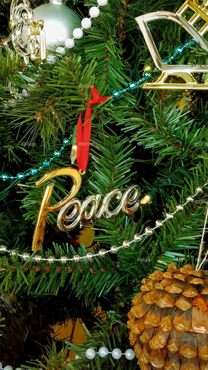Close up of Christmas ornaments on a tree with a focus on the word "peace"