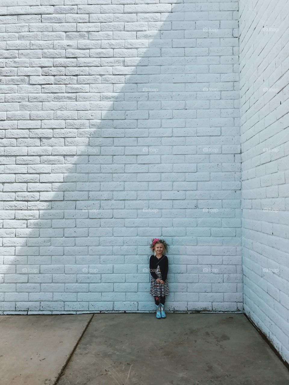 Little girl standing against a white wall. 