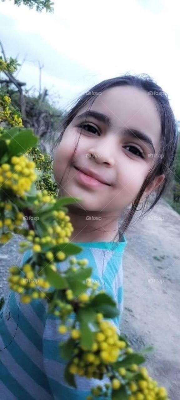 pretty asian teenager with charming smile in a frame of yellow barberry flowers