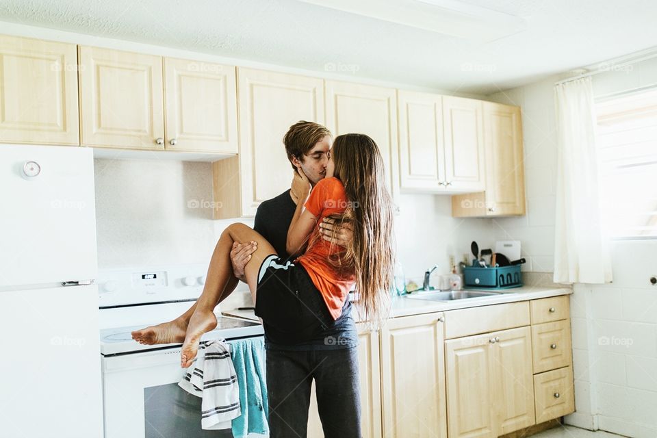 Couple happily kisses in their kitchen.