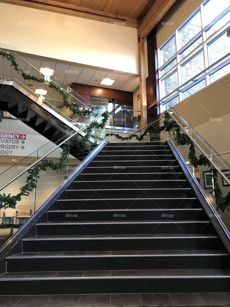Two levels of stairs decorated in festive garland for the holiday season lead to an upper floor. 