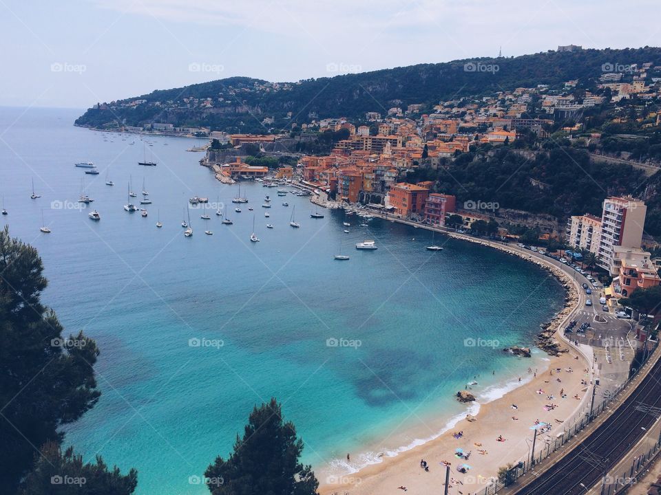 Bay on the French Riviera with beach and town. Overlook of sailboats and beach in a with calm blue water in south France. 