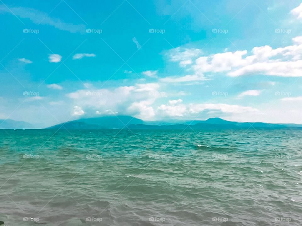 Blue ocean, blue landscape, mountains and sea , beautiful water with blue color, in the blue sky there are many white clouds 