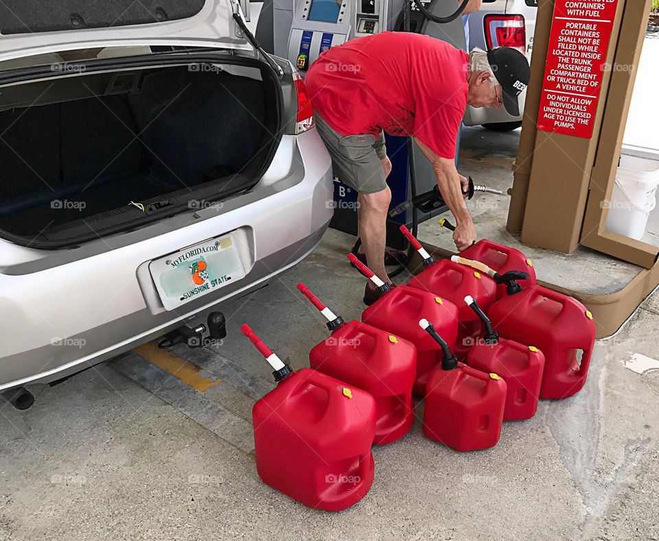 Man filling a repetitive row of gas cans.