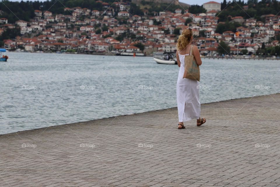 Woman walking by the lake in summertime 