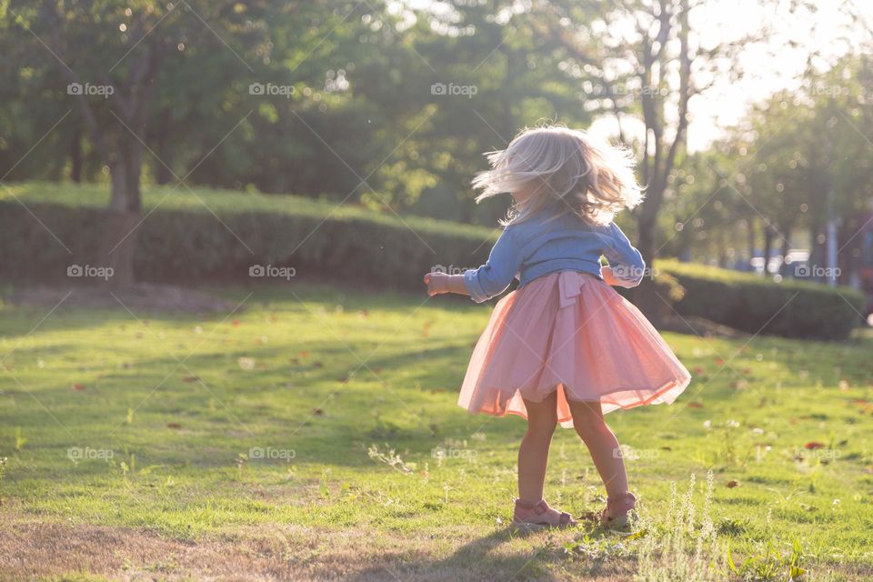 Lifestyle portrait of happy little girl spinning outdoor 