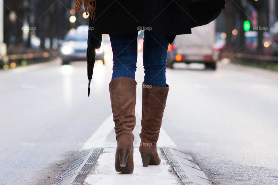 Woman in boots walking in the middle of the street